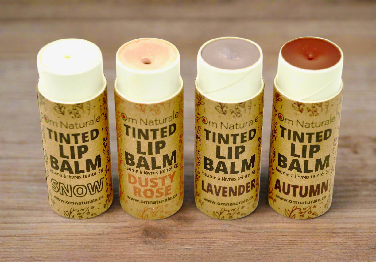 Om Naturale Tinted Lip Balm Starter Set with lids off, showing natural clay colours of each balm — Autumn (maroon), Snow (white), Dusty Rose (pink), Lavender (light purple) in compostable tubes