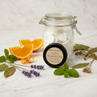 Om Naturale Buddha 120-count compressed towel refill jar displayed with a Buddha Shower in a Tin and botanicals.