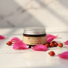 Om Naturale Rosehip & Rose Petal Eye Cream displayed in a relaxing botanical skincare setting with the jar closed.