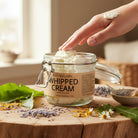 Whipped shea body cream displayed with wildharvested comfrey – organic, nourishing moisturizer for whole body, light airy texture from Om Naturale farm in BC